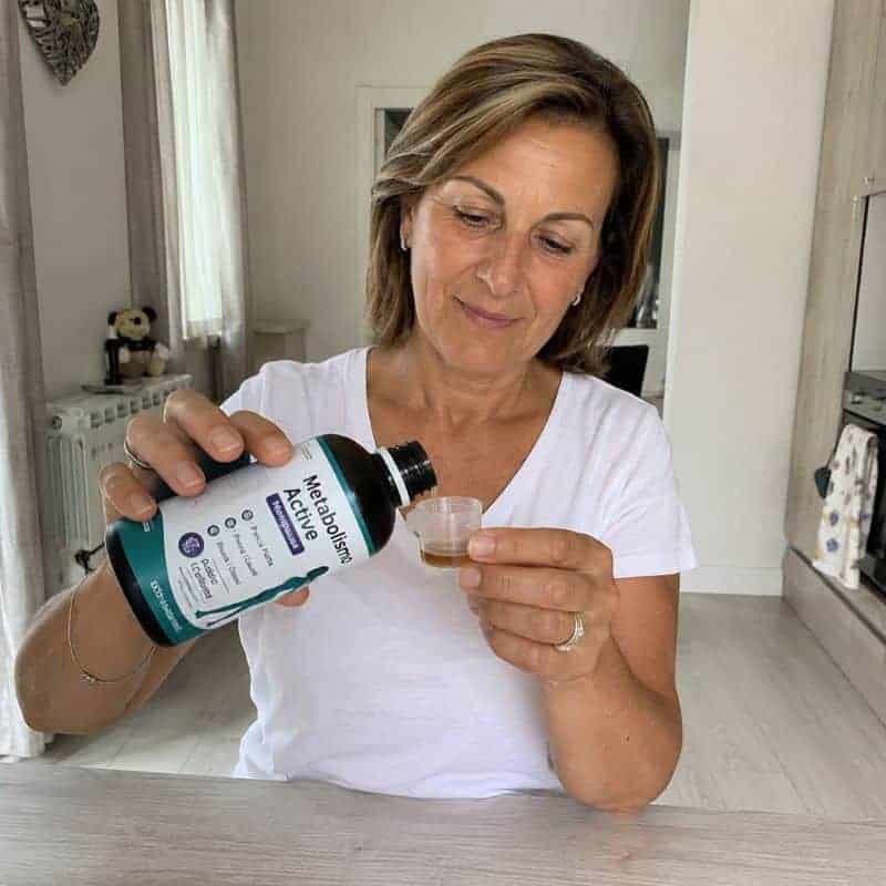 Donna versa integratore Metabolismo Active 1x in un bicchiere.